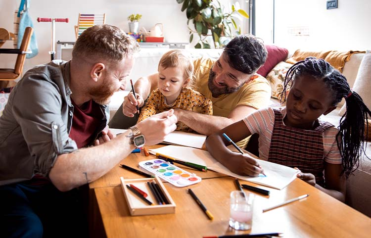 Deux adultes et deux enfants assis à une table basse s'amusant avec des livres de coloriage.