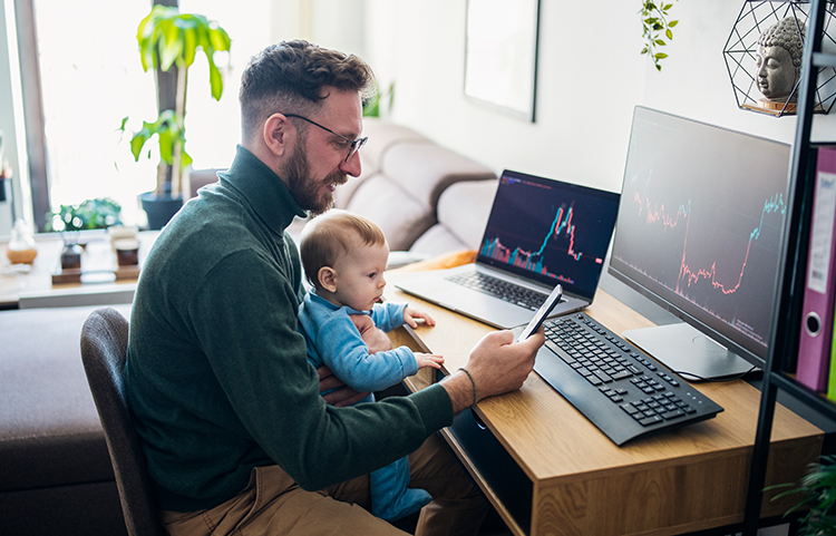 Personne assise à son bureau d'ordinateur avec son enfant en bas âge sur les genoux.